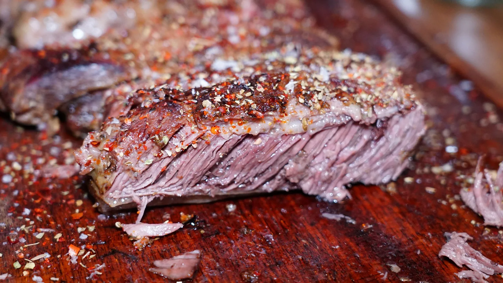 Fatias suculentas de bife temperadas com especiarias, servidas em uma tábua de madeira, exibindo uma textura de dar água na boca.