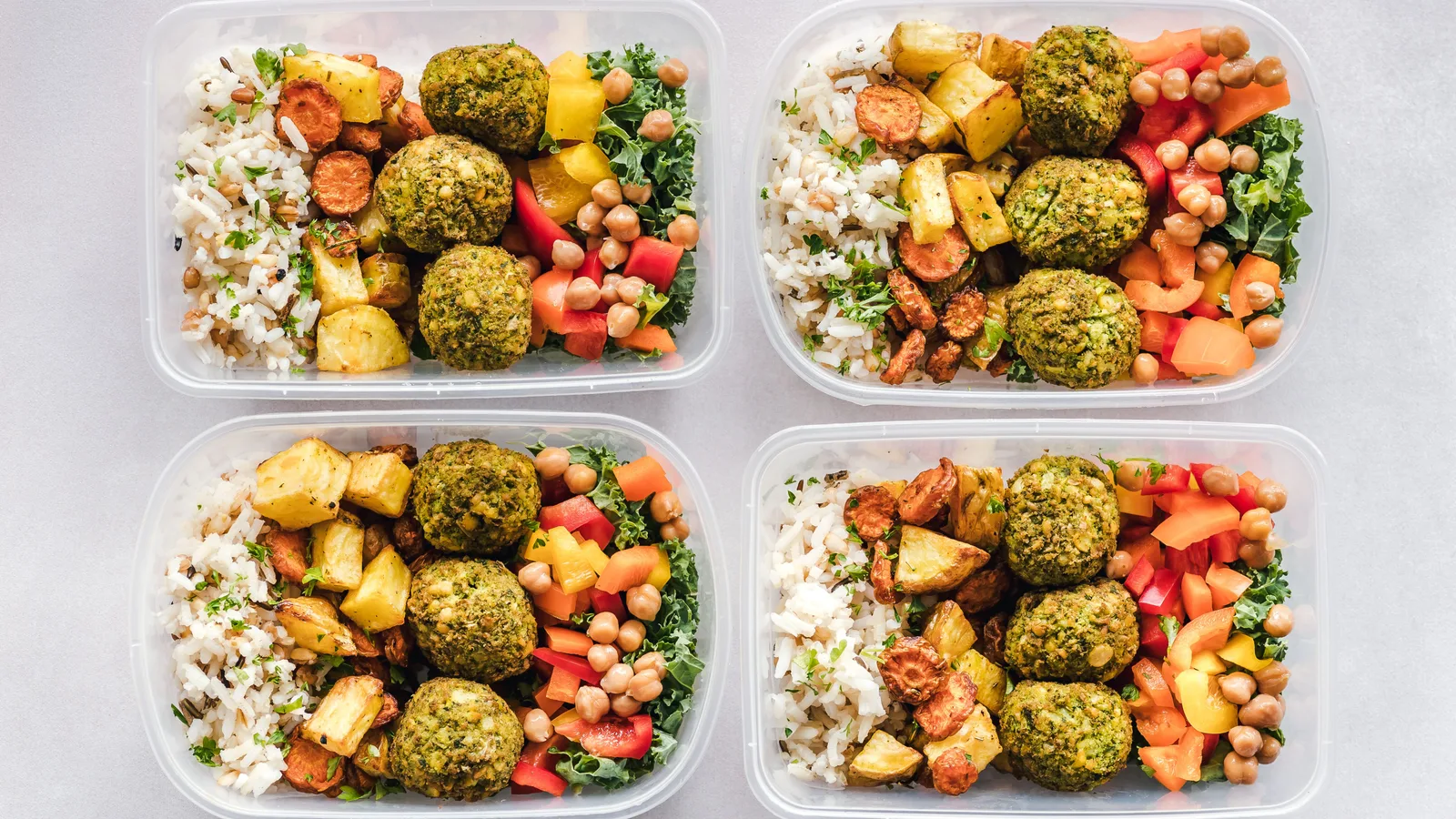 Recipientes coloridos de preparo de refeições com falafel, grão-de-bico, arroz e vegetais para um estilo de vida saudável.